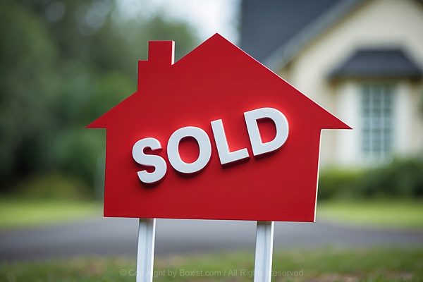 Sold In White On Red House Shaped Sign Against Blurry House Background