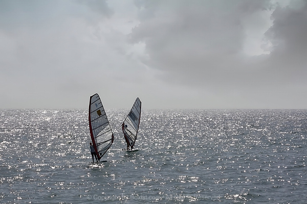 Two Windsurfing Sails Gliding Across The Open Sea