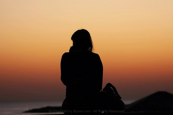 Woman Silhouette Contemplating Fading Sunset Colors On Beach