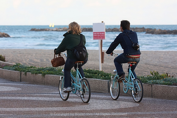 Couple Riding Bicycles And Cycling Together Along Coastal Pathway