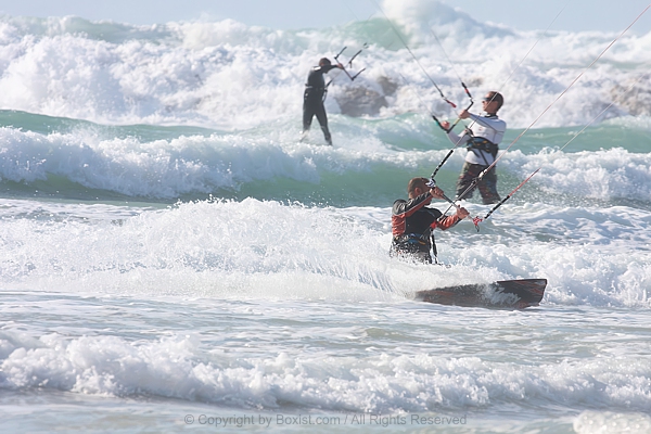 Group Of Kitesurfers Riding Stormy Waves In The Sea
