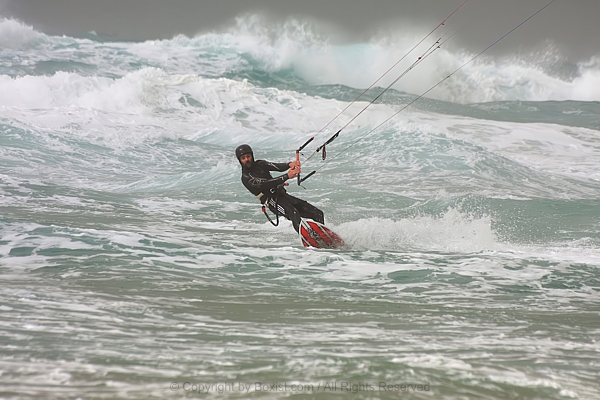 Man Kitesurfing In Stormy Ocean Riding Waves
