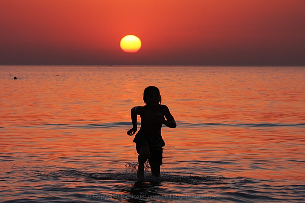 Boy Running In Water At Sunset