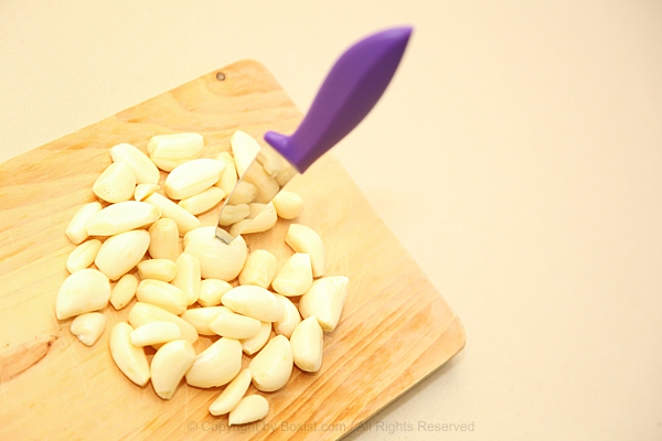 Freshly Peeled Garlic Cloves With Knife On Wooden Board