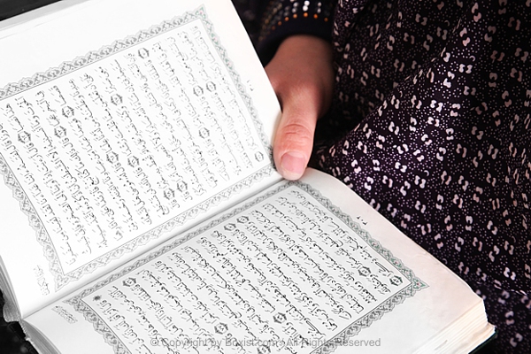 Person Holding And Reading Open Quran Book