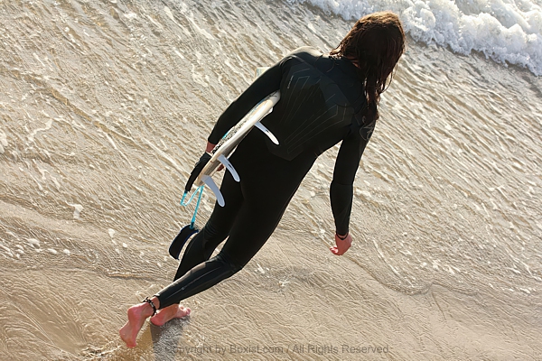 Man Walking With His Surfing Board On The Beach