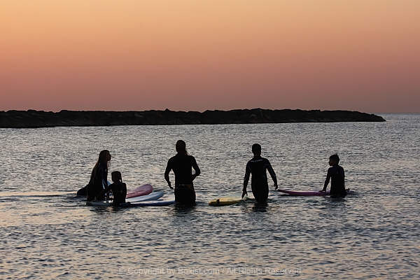 Family Silhouettes Preparing To Surf At Sunset