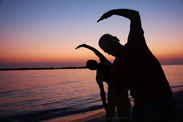 Silhouette Of People Exercising On The Beach At Susnet