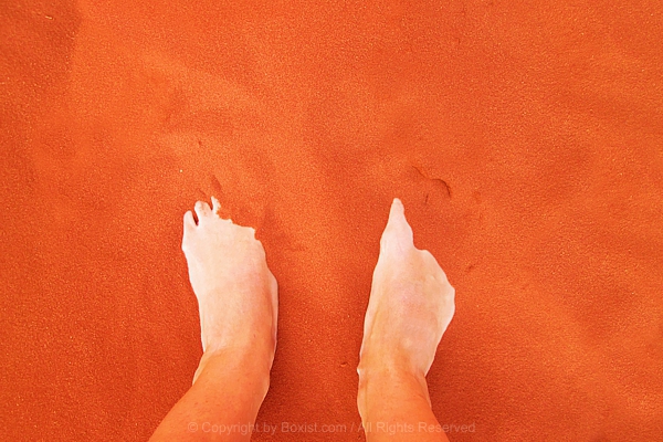 Person Standing Barefoot On Warm Vibrant Orange Sand