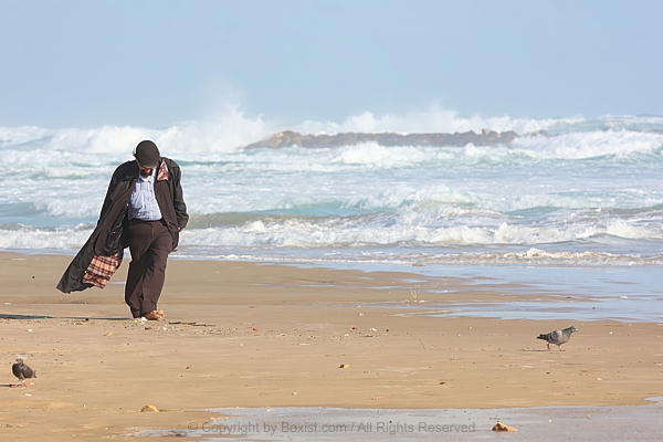 Lonely Senior Strolling Along Beach With Crashing Waves