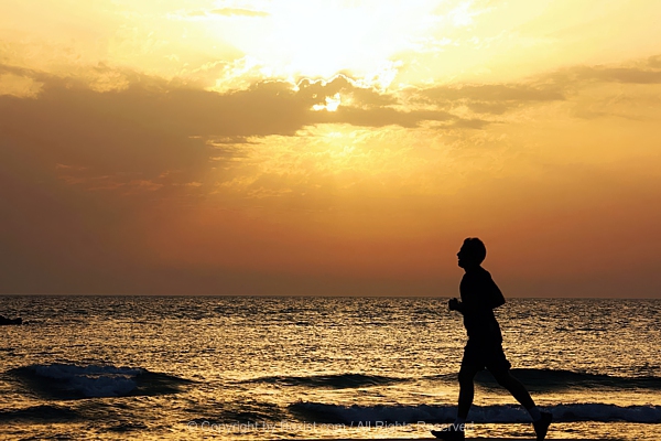 Jogger Silhouette On Sunset Beach Shoreline