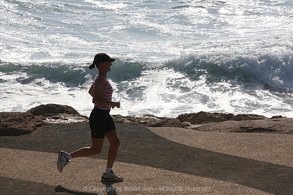 Woman Jogging Along Beach Shoreline