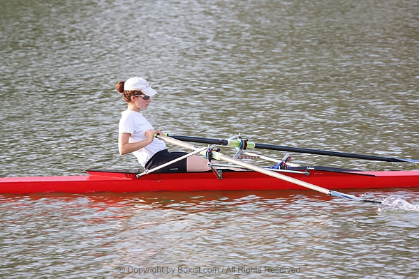 Young Woman Rowing Single Scull On Lake