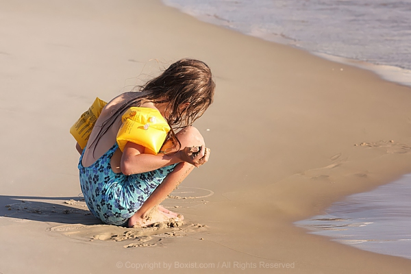 Child In Floaties Playing With Sand At Shoreline