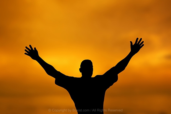 Person Raises Arms In Triumph Against Vibrant Evening Sky