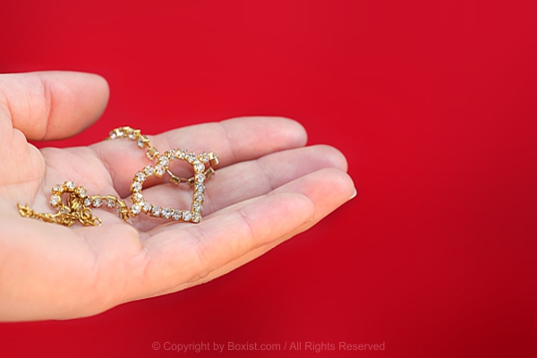 Hand Holds Shiny Gold Necklace With Heart Pendant