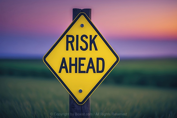 Risk Ahead Road Sign Against Blurry Landscape At Sunset