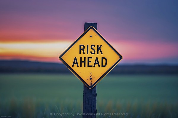 Road Sign With Risk Ahead Warning On Wooden Post Against Blurred Landscape Background
