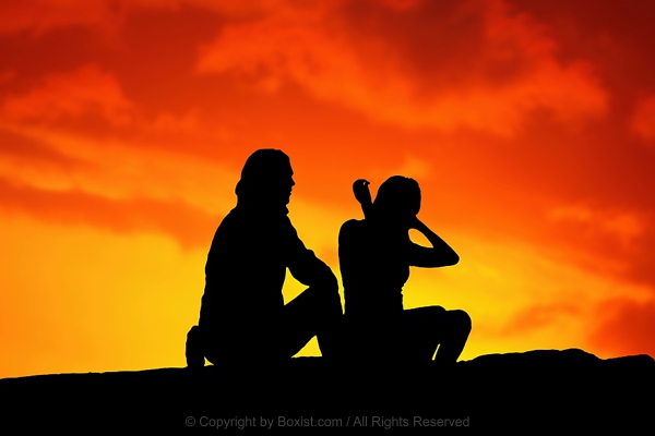 Silhouetted Couple Seated Against Sunset Background