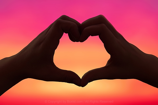 Two Hands In Love Heart Shape Against Blurry Sunset Sky Background