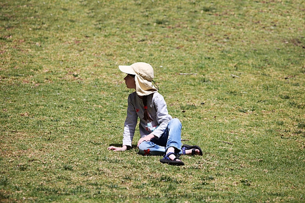 Young Kid Sitting On Green Grass