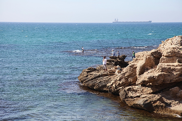  Rocky Shoreline In The Mediterranean With Several Individuals Fishing From The Rocks